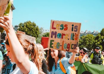 A girl holding a banner saying less is more.