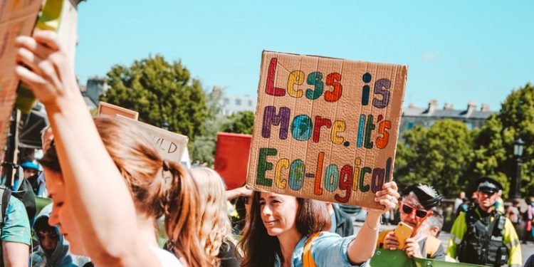 A girl holding a banner saying less is more.