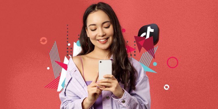 A TikTok creator dancing on an autumn-colored street with a phone tripod.