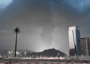 Dubai skyline at night with influencers filming unexpected explosions in the distance