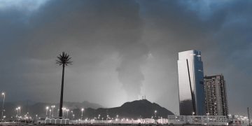 Dubai skyline at night with influencers filming unexpected explosions in the distance
