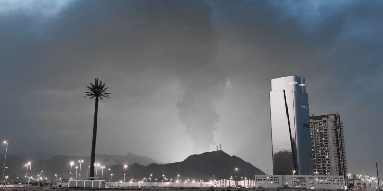 Dubai skyline at night with influencers filming unexpected explosions in the distance